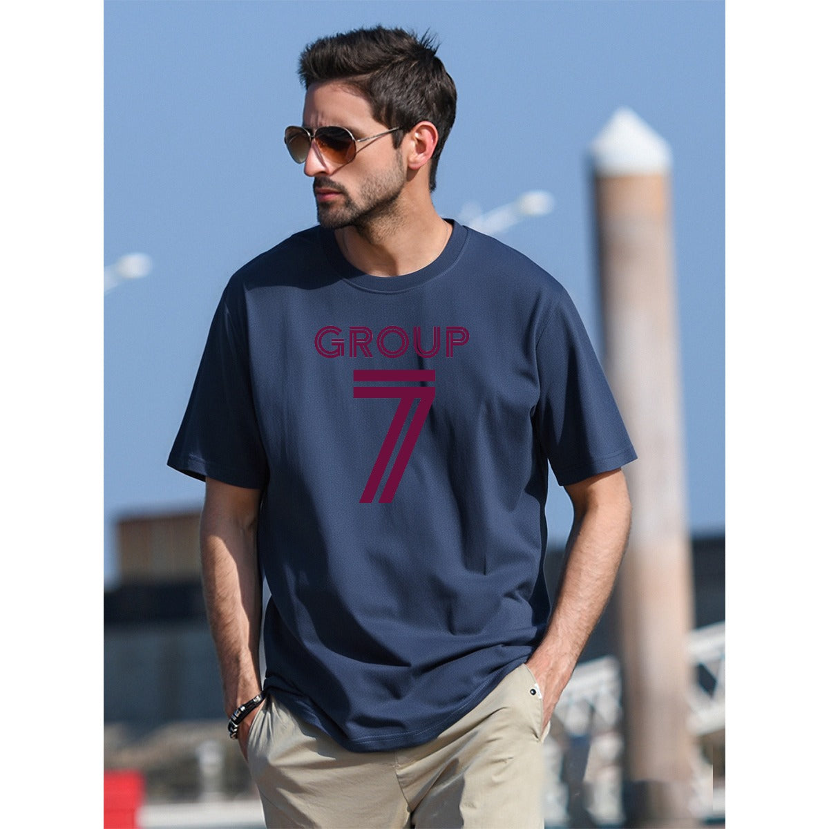 Man wearing a navy blue t-shirt with 'GROUP 7' printed on it, standing outdoors.