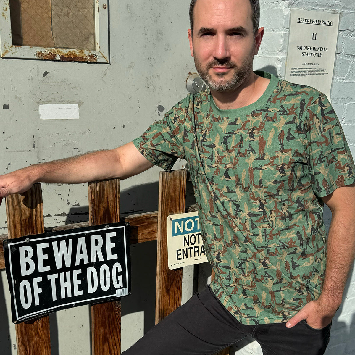 person standing by fence wearing a Kama Sutra Camo Sexy NSFW T-shirt