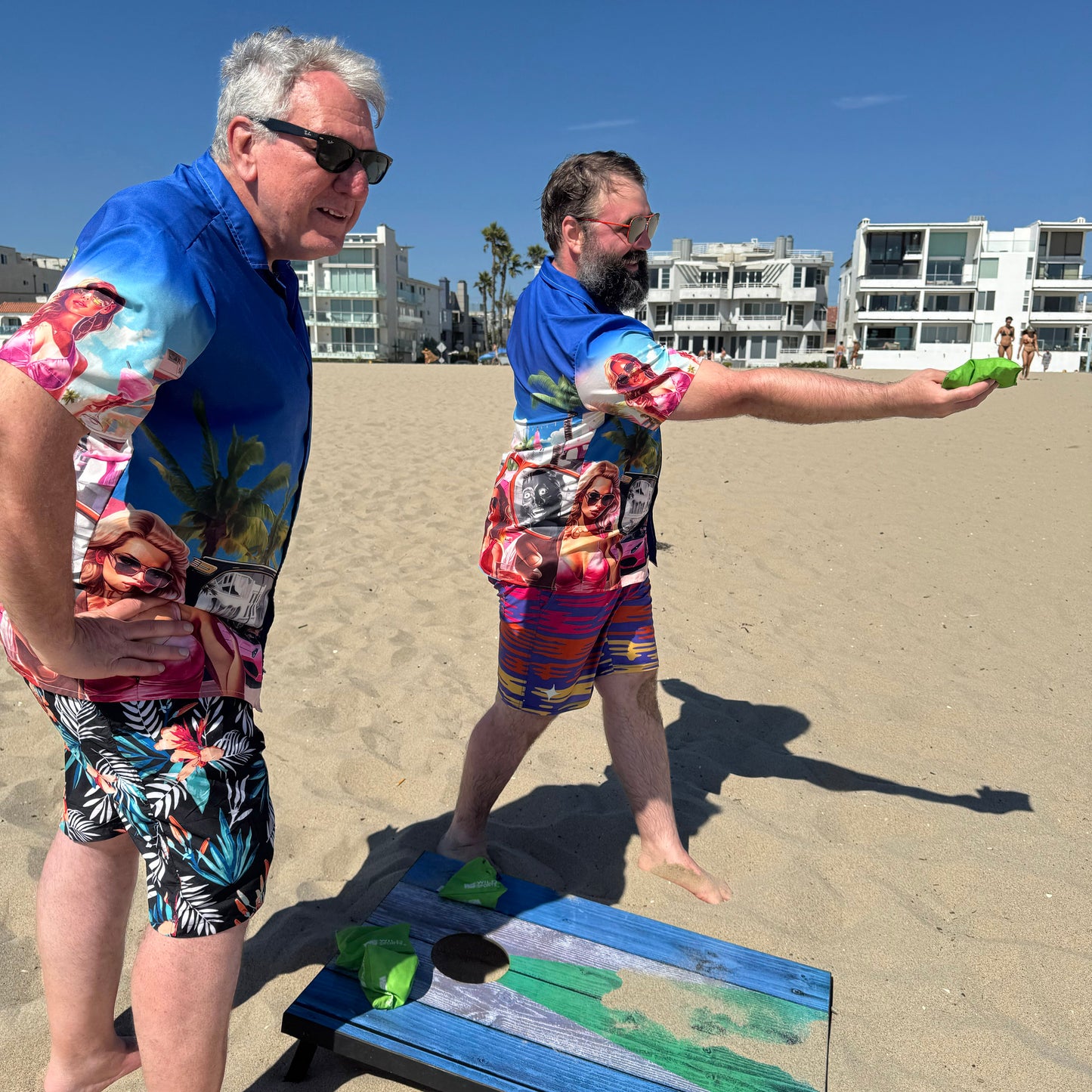 Two guys wearing They Live Miami-flavored Hawaiian style button down shirt at beach