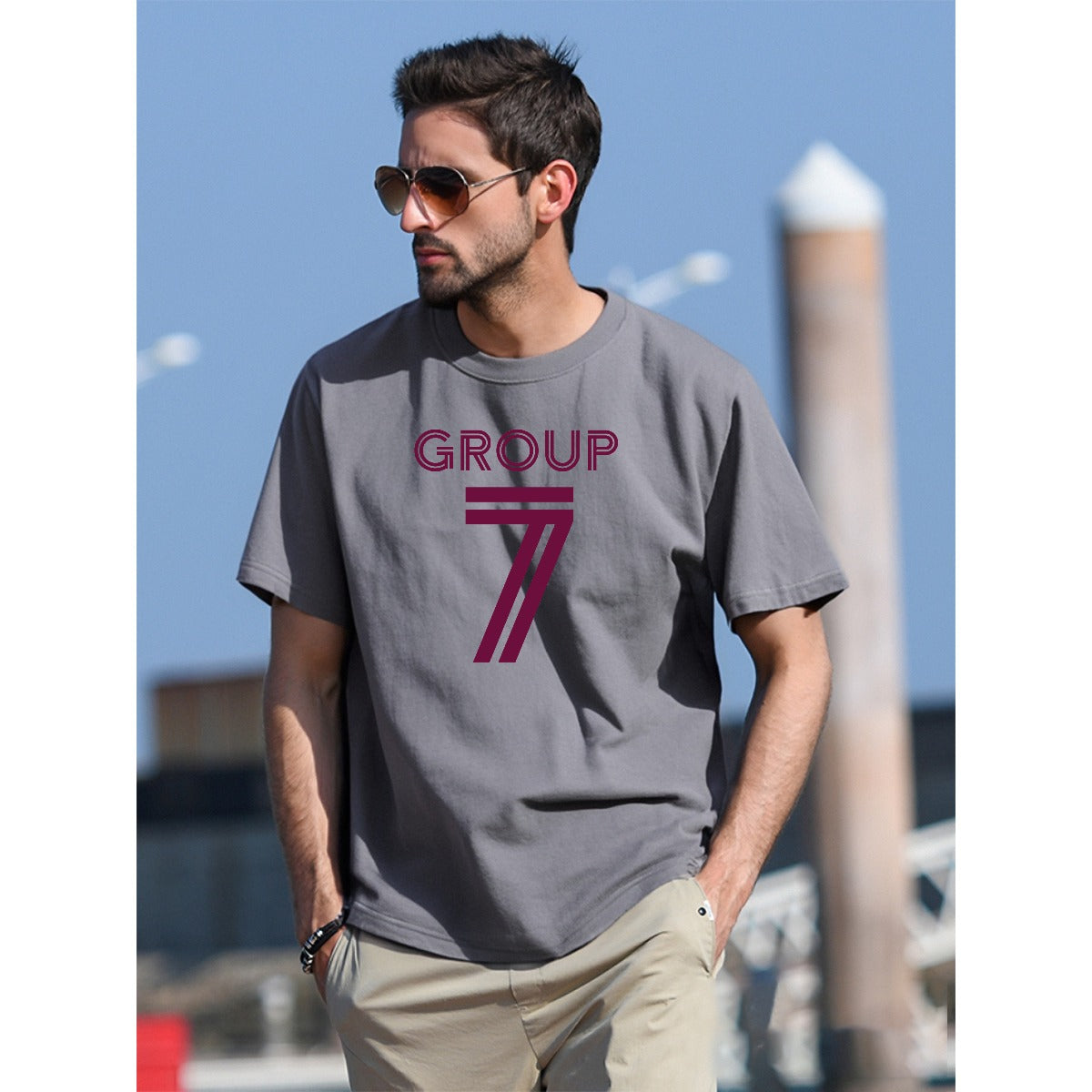 Man wearing a gray t-shirt with 'GROUP 7' logo outdoors